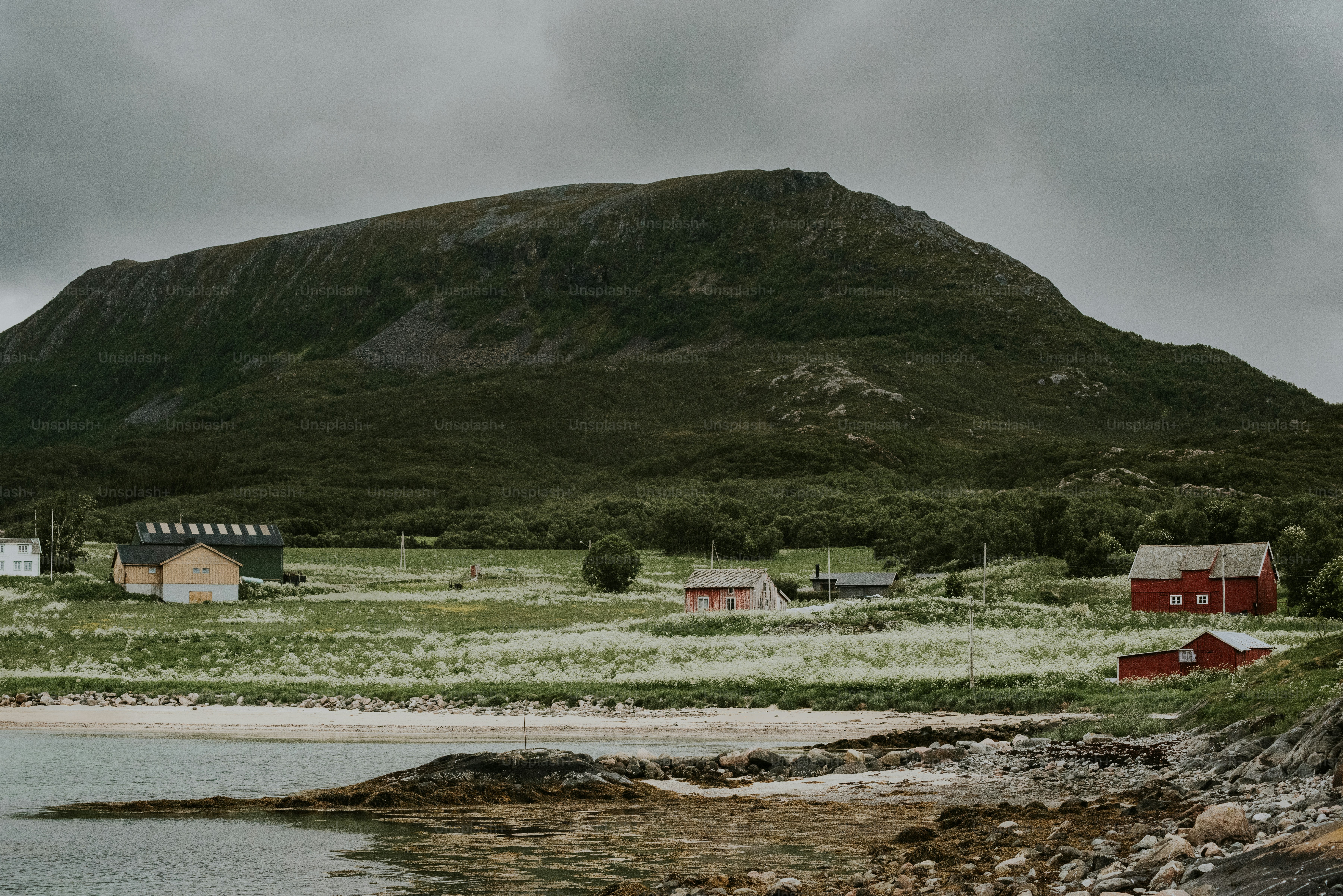 a mountain with a house on it and a body of water in front of it