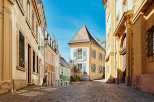 a cobblestone street lined with yellow buildings