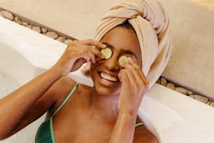 a woman with cucumbers on her eyes in a bathtub