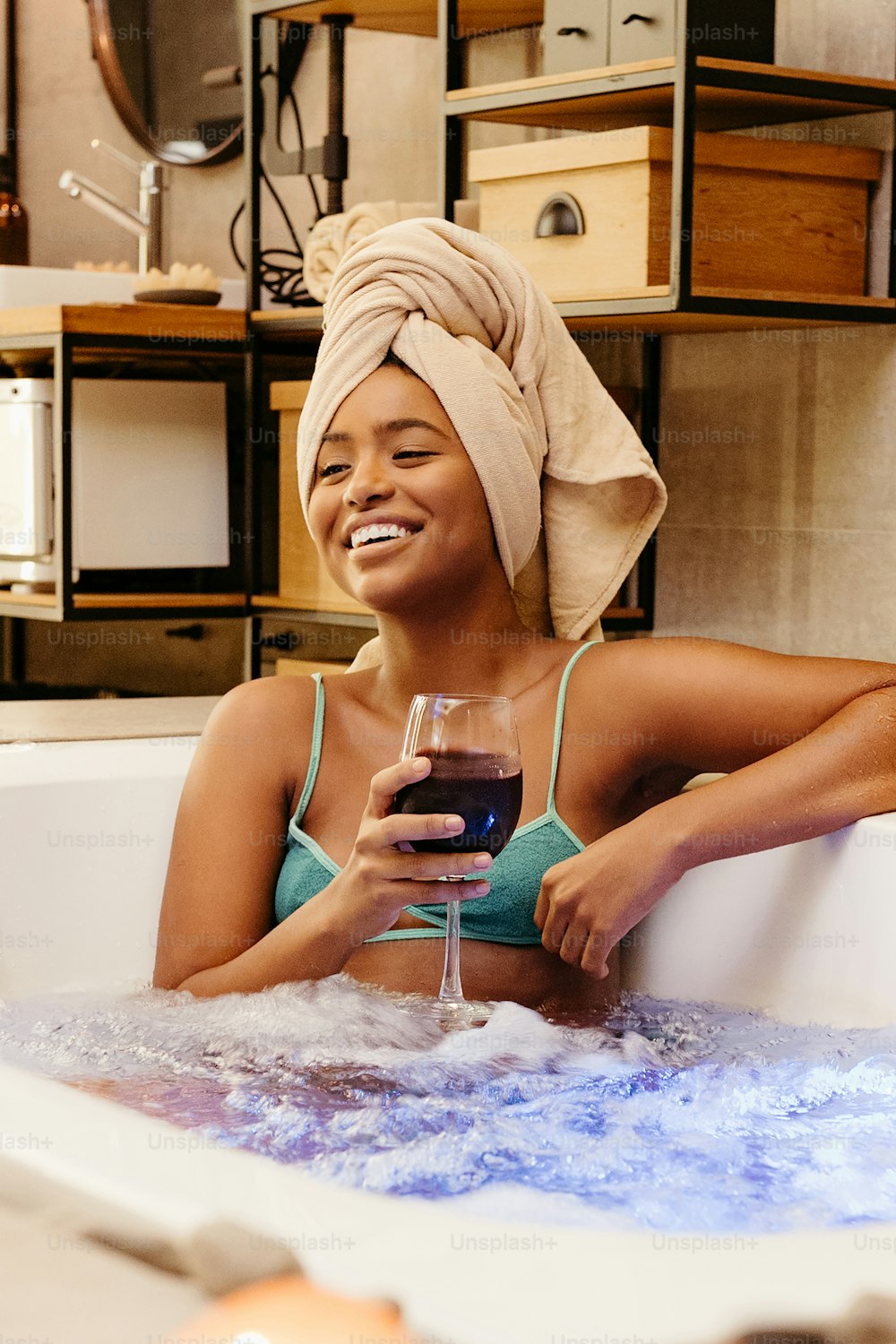 Una mujer sentada en una bañera sosteniendo una copa de vino