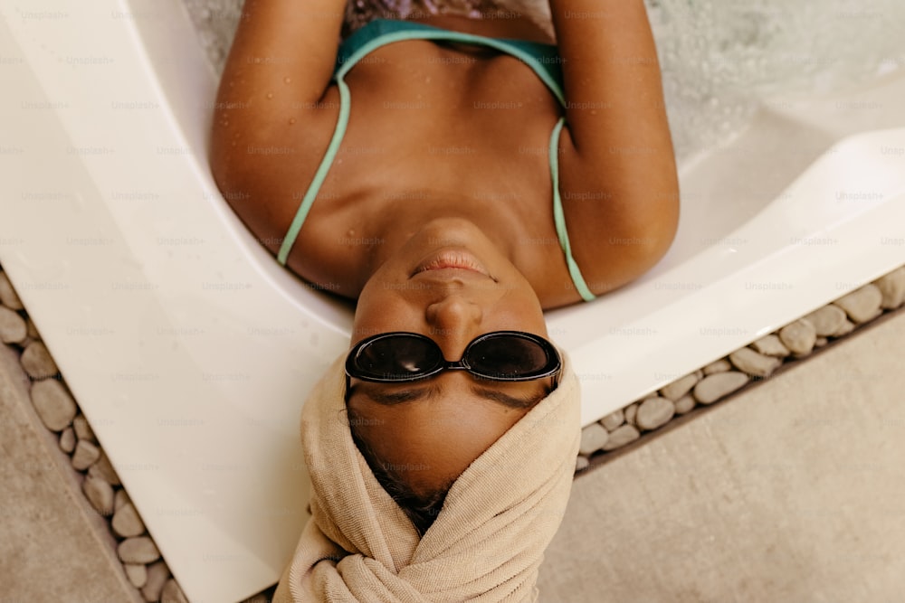 a woman laying in a bathtub with a towel wrapped around her