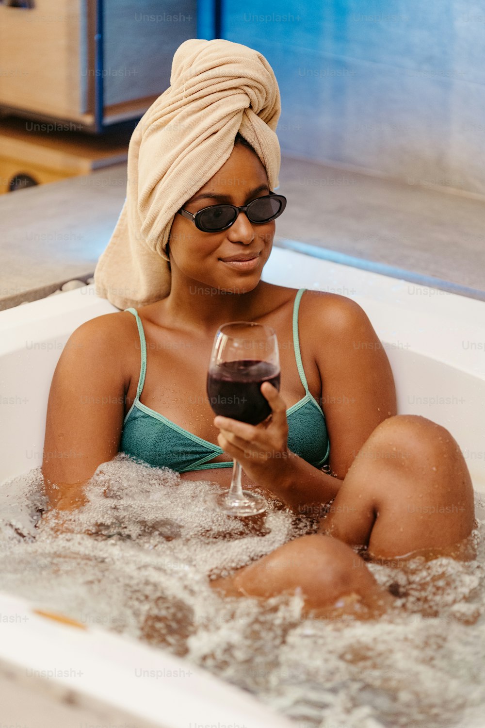 a woman in a bathtub holding a glass of wine