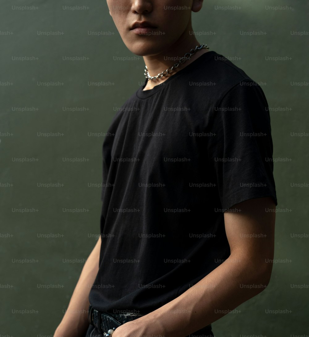 a young man wearing a black shirt and a chain around his neck