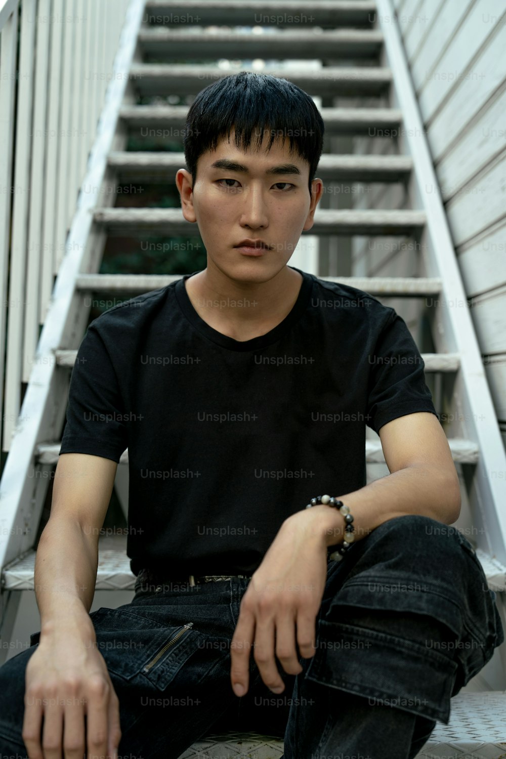 Ein junger Mann, der auf den Stufen eines Gebäudes sitzt