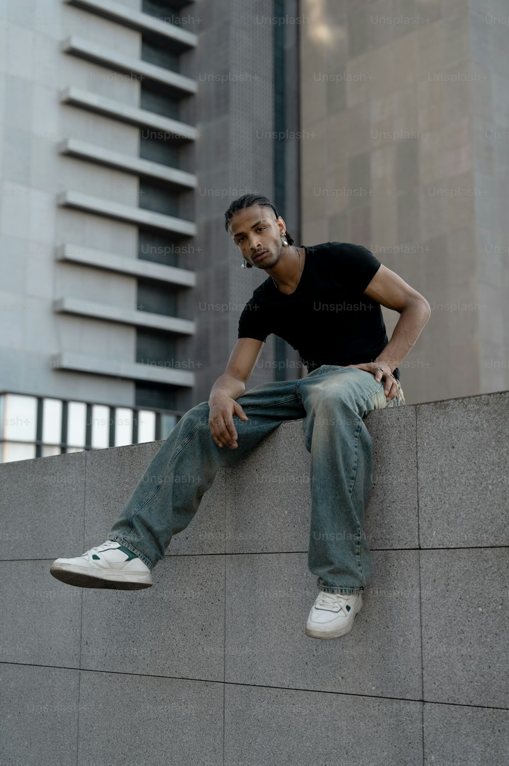 a man sitting on a wall talking on a cell phone