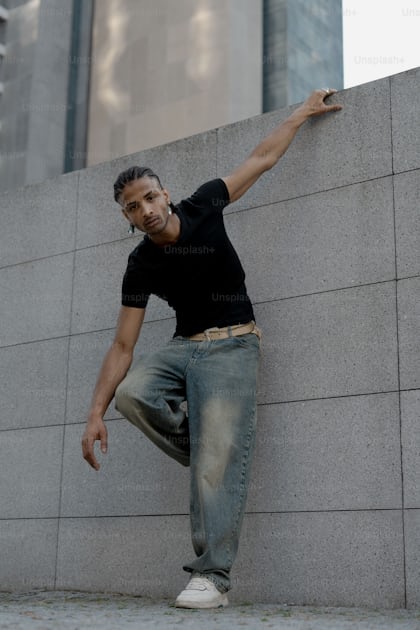 Hombre Arafed parado frente a una pared con las manos en las caderas, foto  de retrato