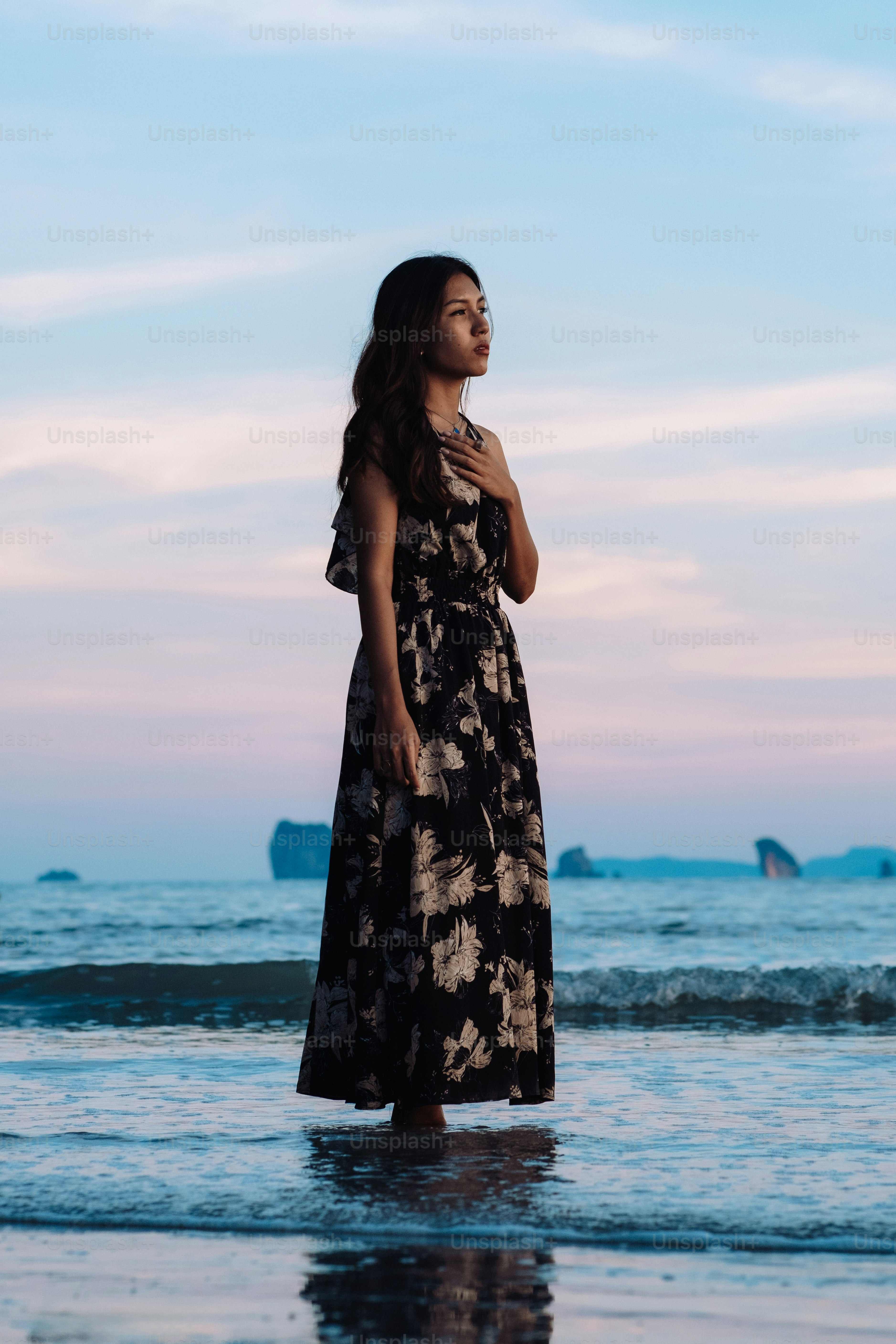 A woman standing on a beach next to the ocean photo – Woman Image on ...