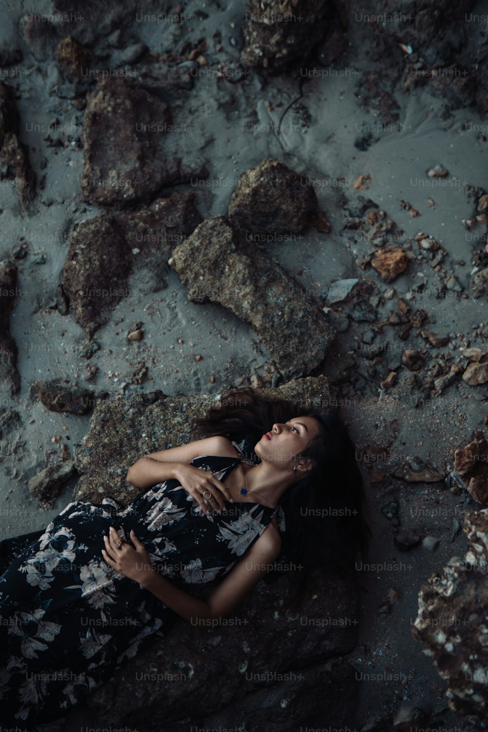 a woman laying on the ground next to rocks
