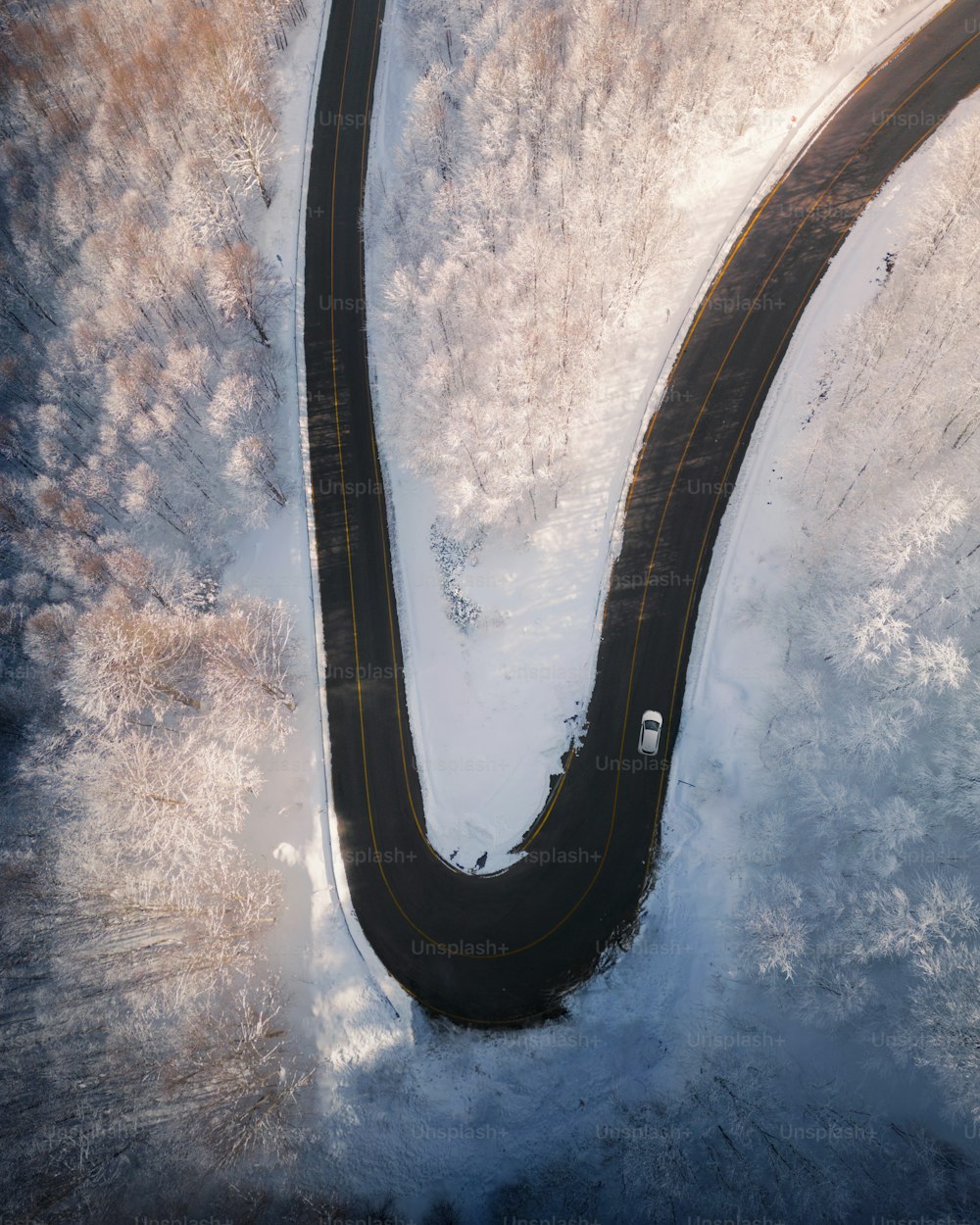 an aerial view of a winding road in the snow