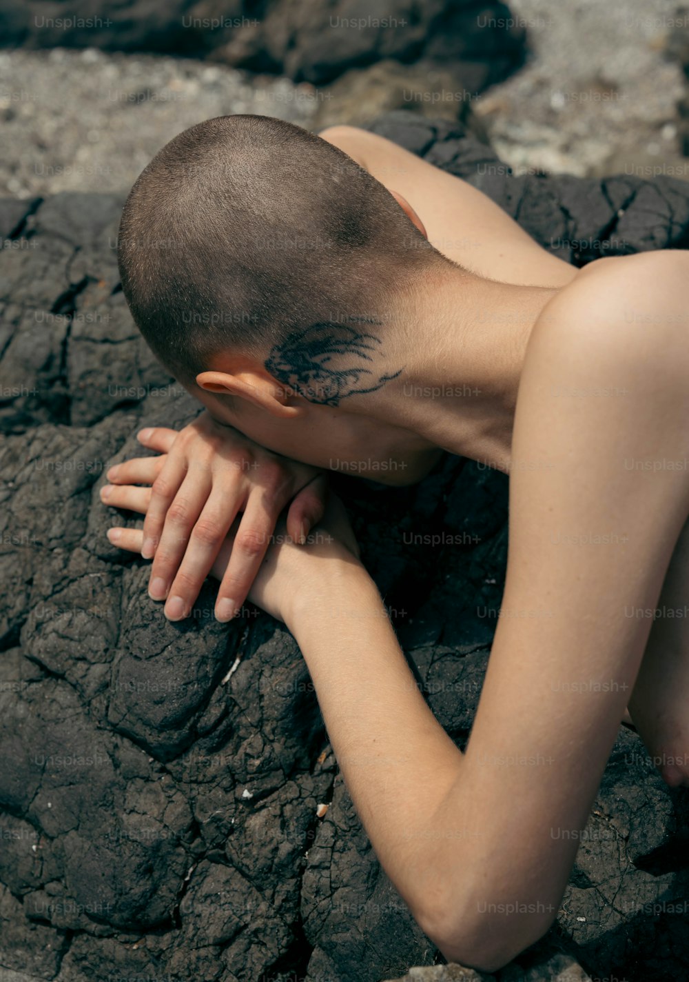 a naked man laying on top of a rocky beach