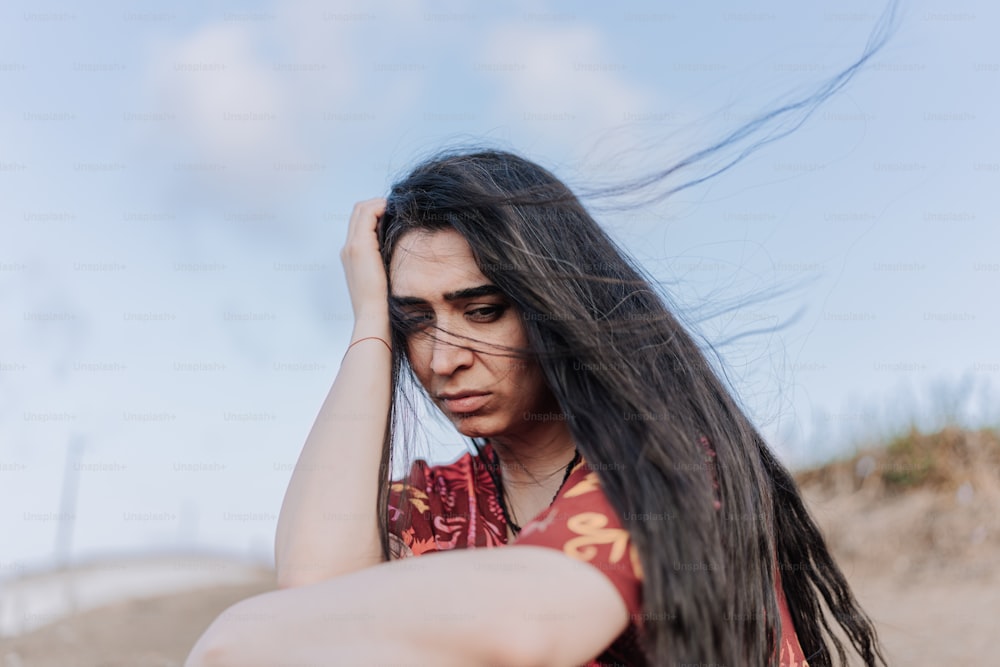 a woman with long hair sitting on a beach