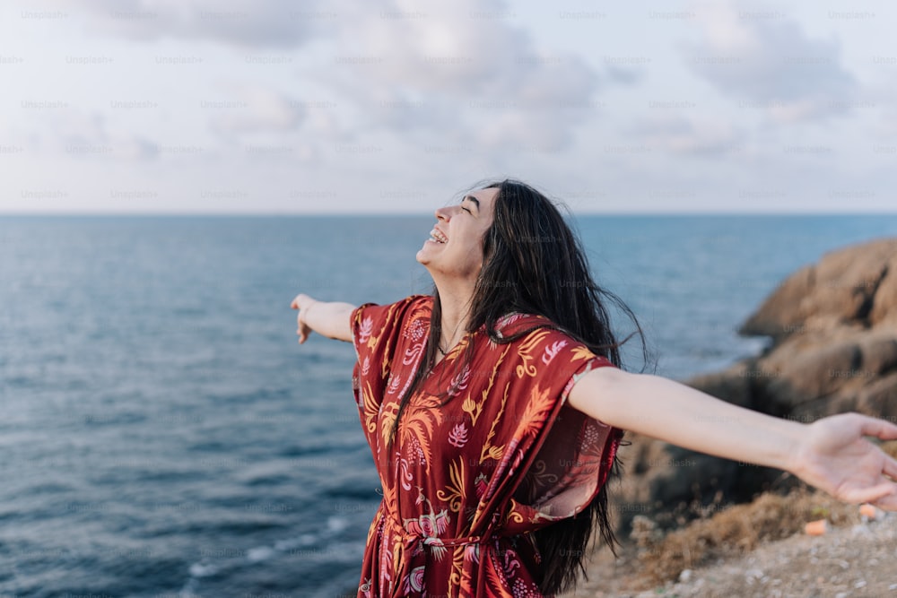 Une femme en robe rouge debout au bord de l’océan