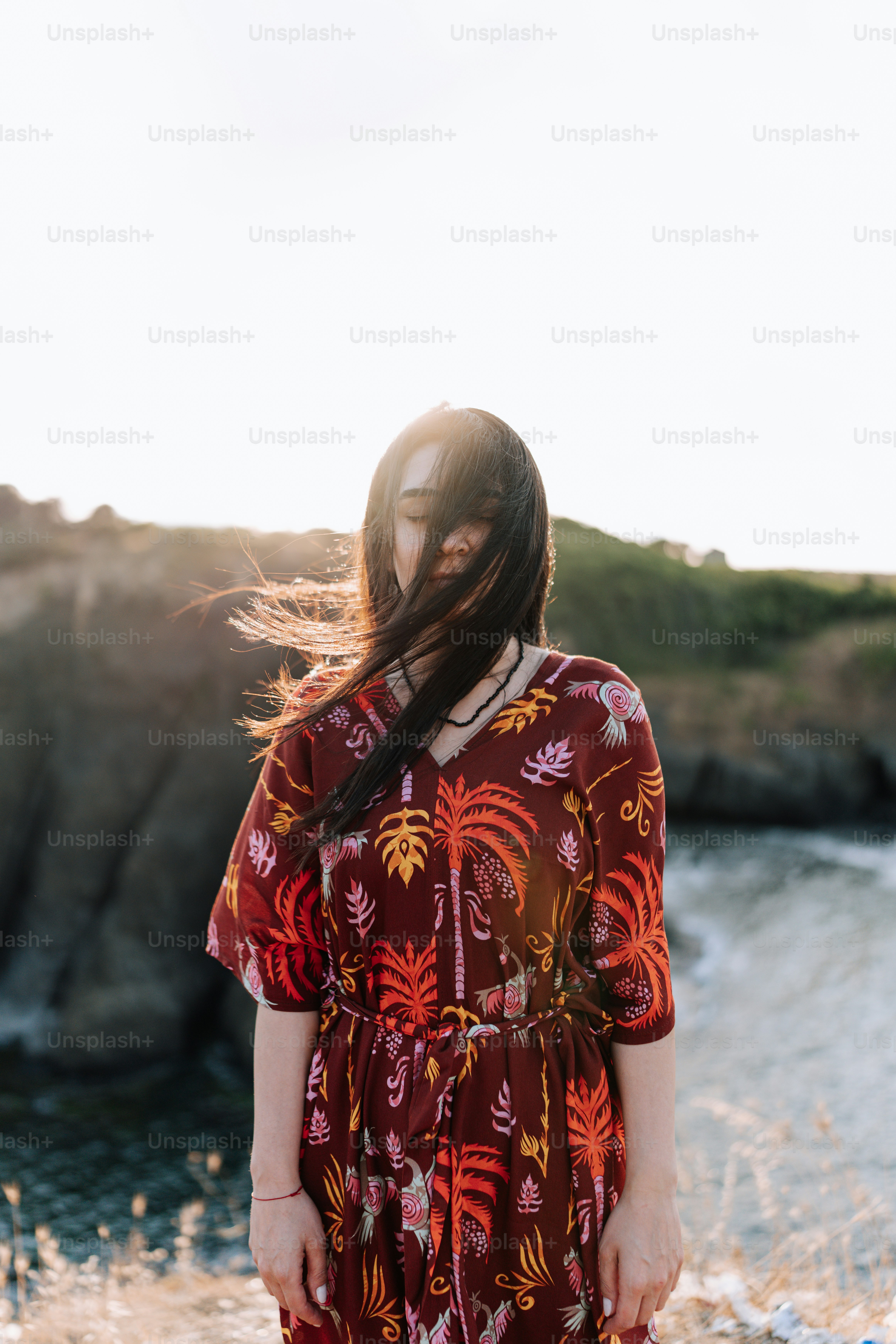 Una donna in piedi su una spiaggia accanto a uno specchio d'acqua