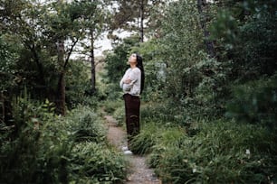 Una mujer parada en medio de un bosque