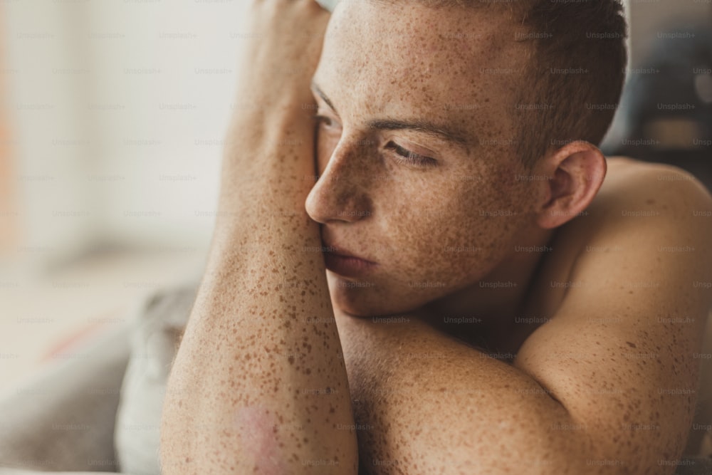 a man with freckles on his body laying on a bed