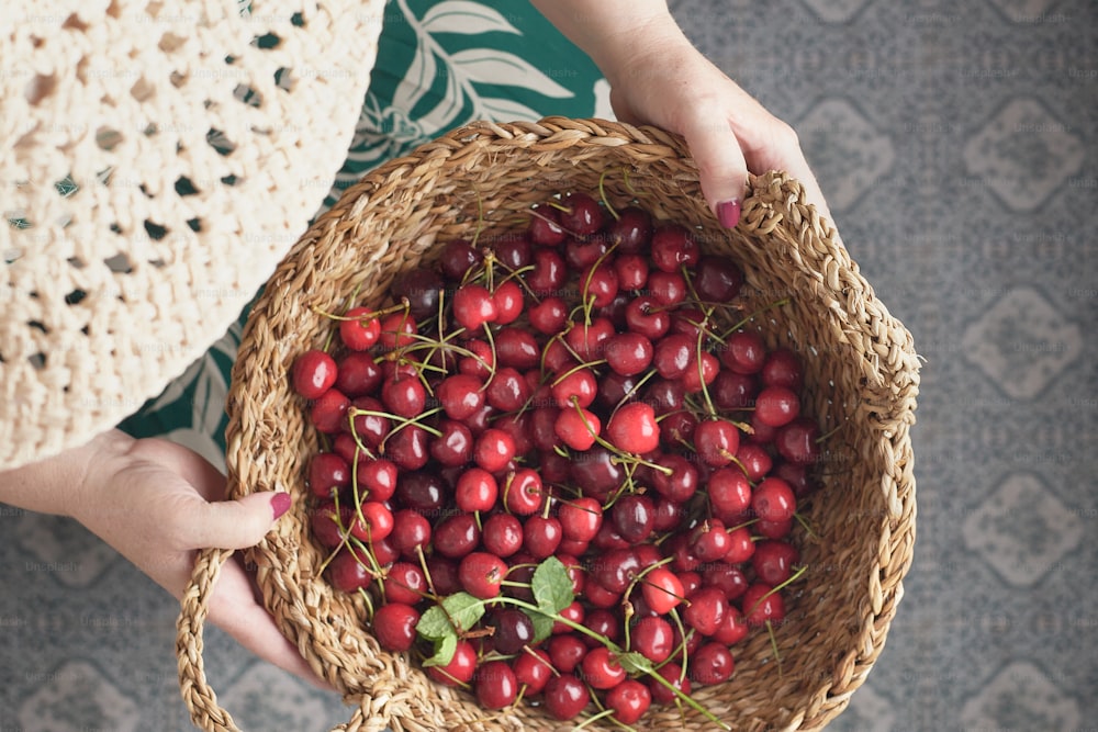 uma pessoa segurando uma cesta cheia de cerejas