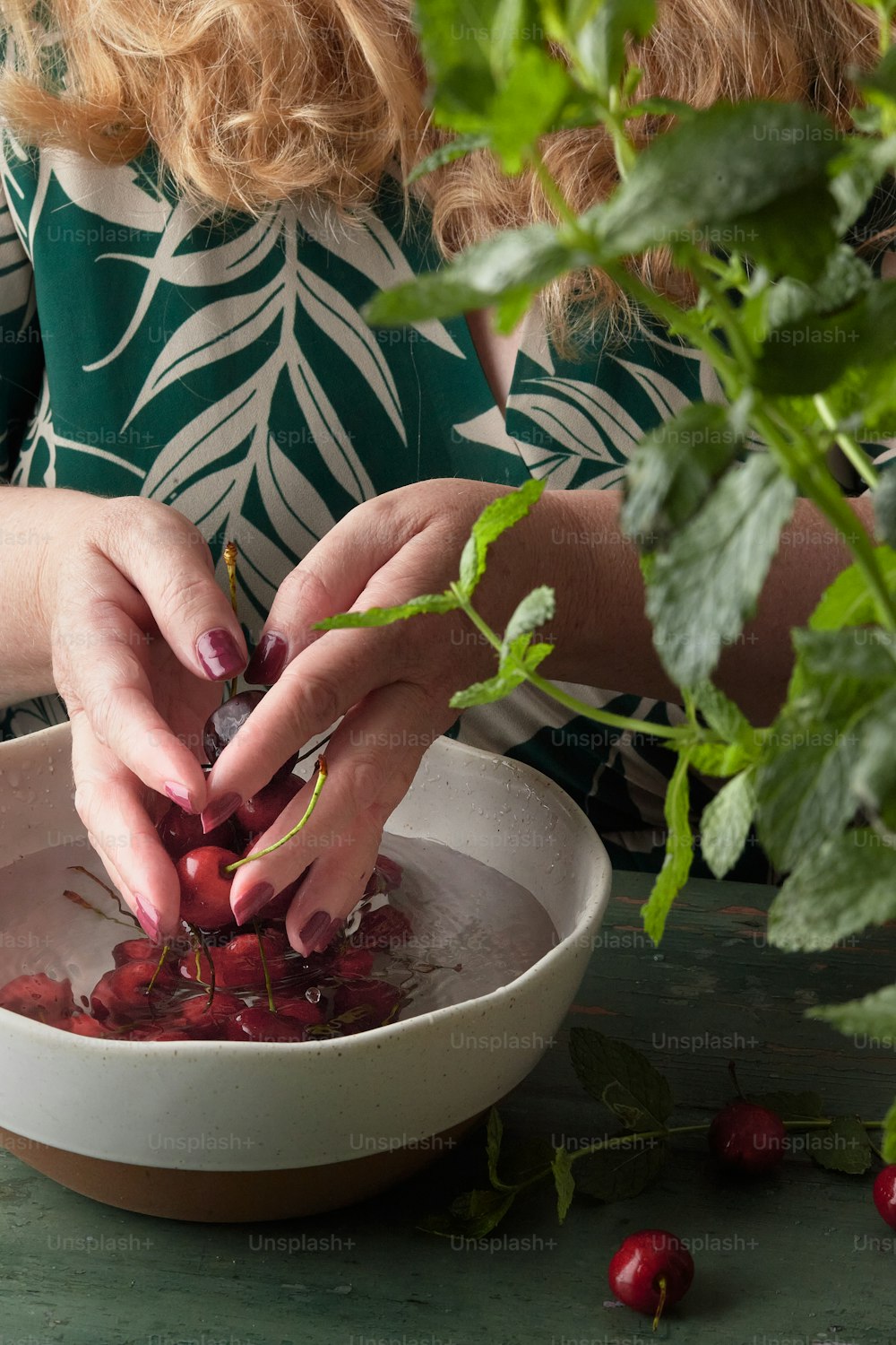 a woman is picking cherries from a bowl