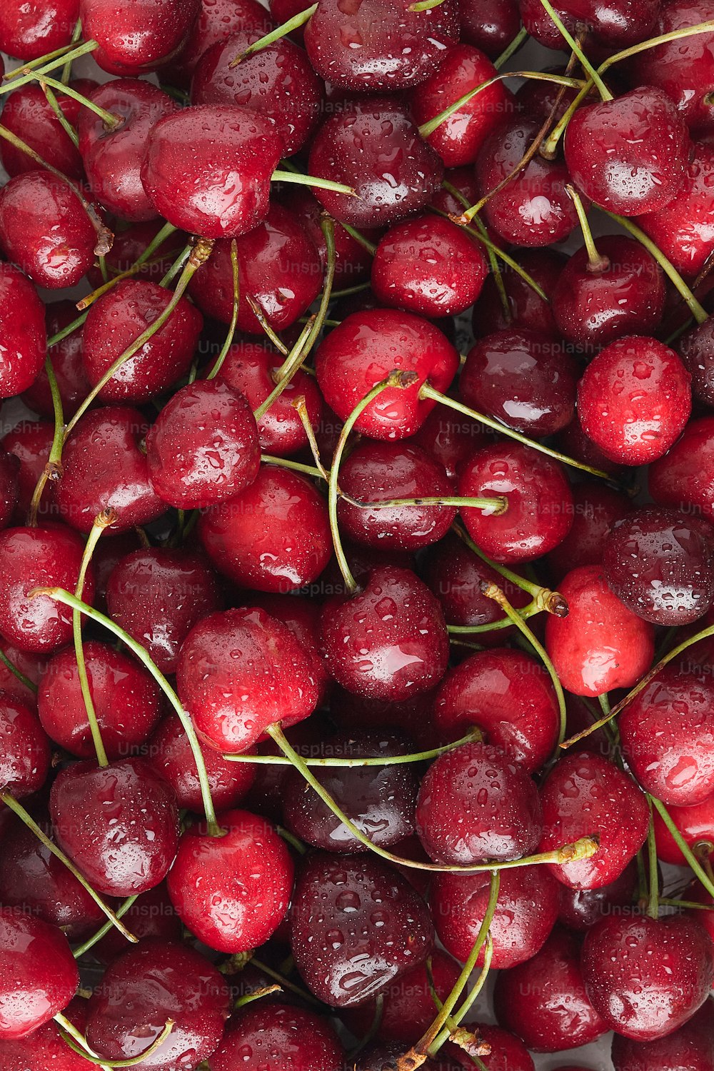 a pile of cherries with water droplets on them