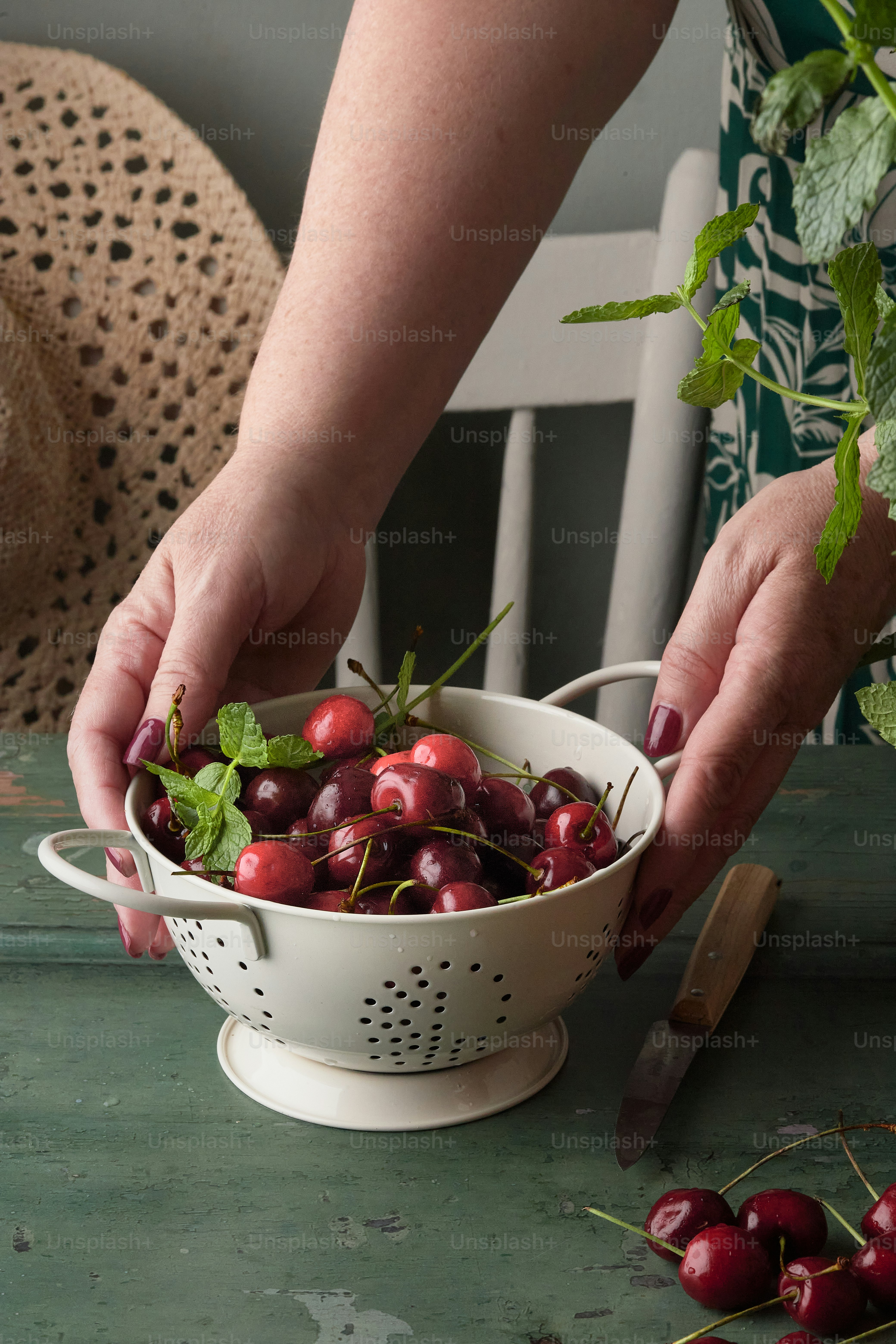 a person picking cherries from a colander