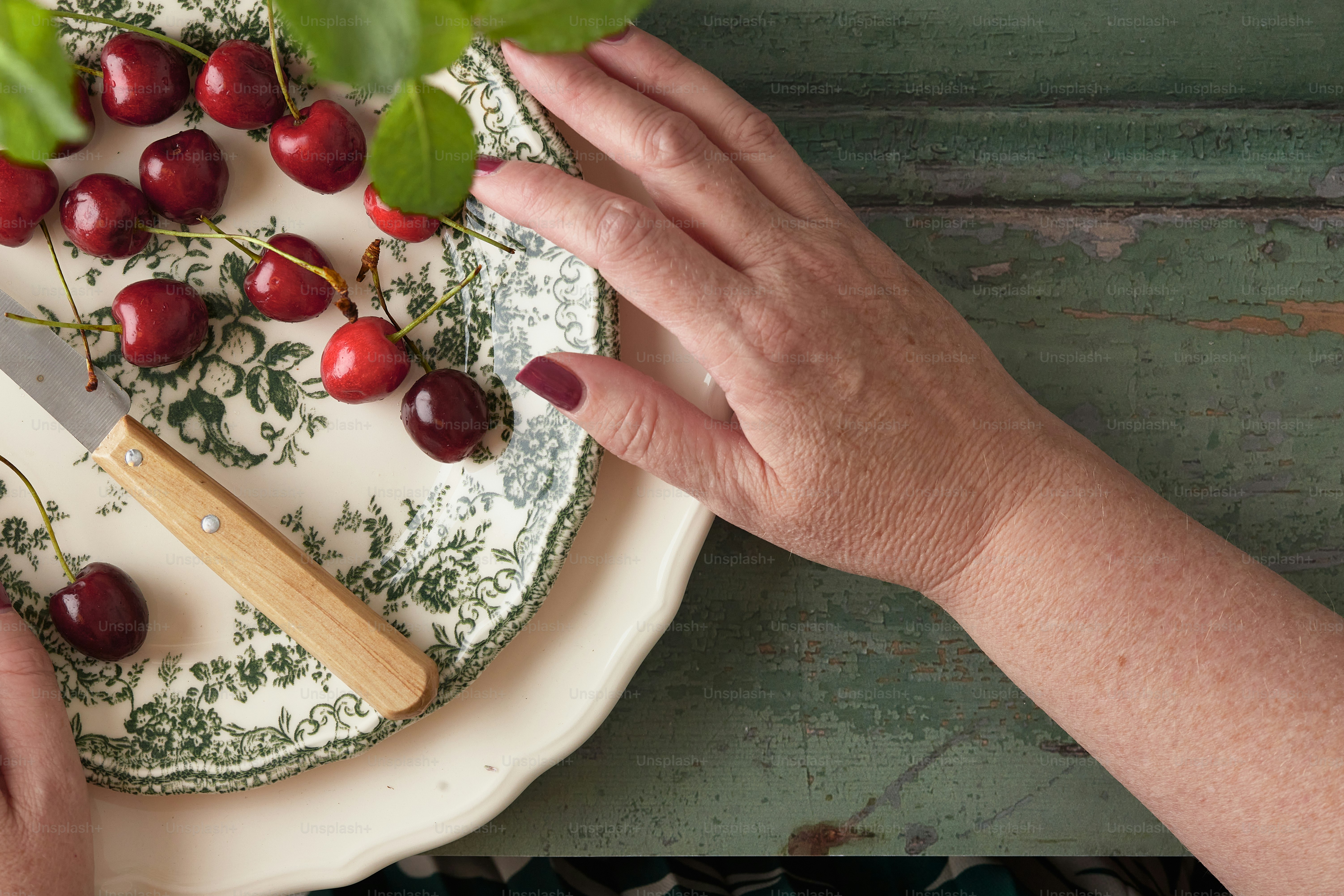 a person cutting cherries on a plate with a knife