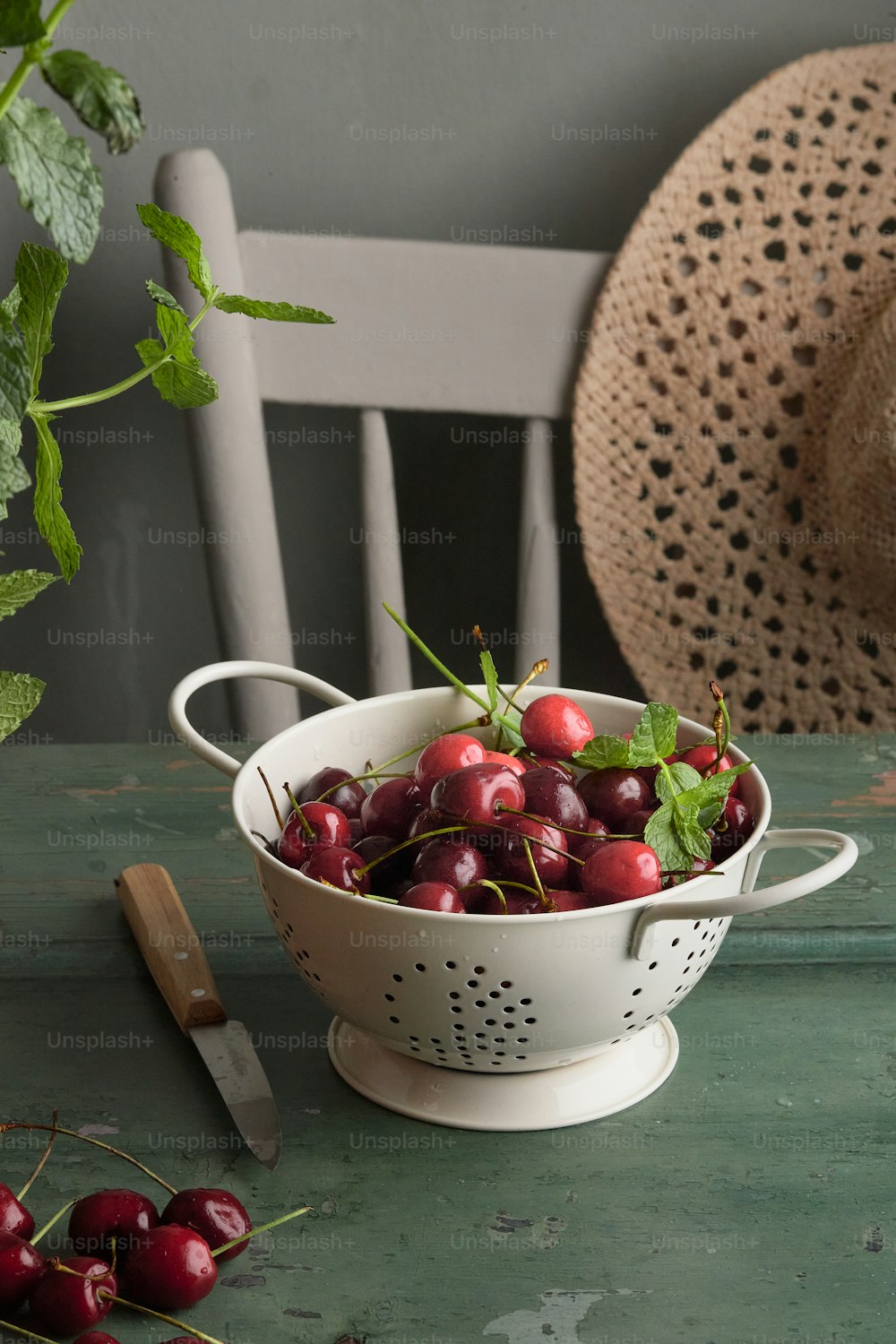 a white colander filled with cherries on a table