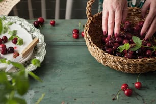 a person picking cherries from a basket on a table