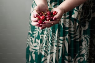 uma mulher segurando um monte de cerejas em suas mãos