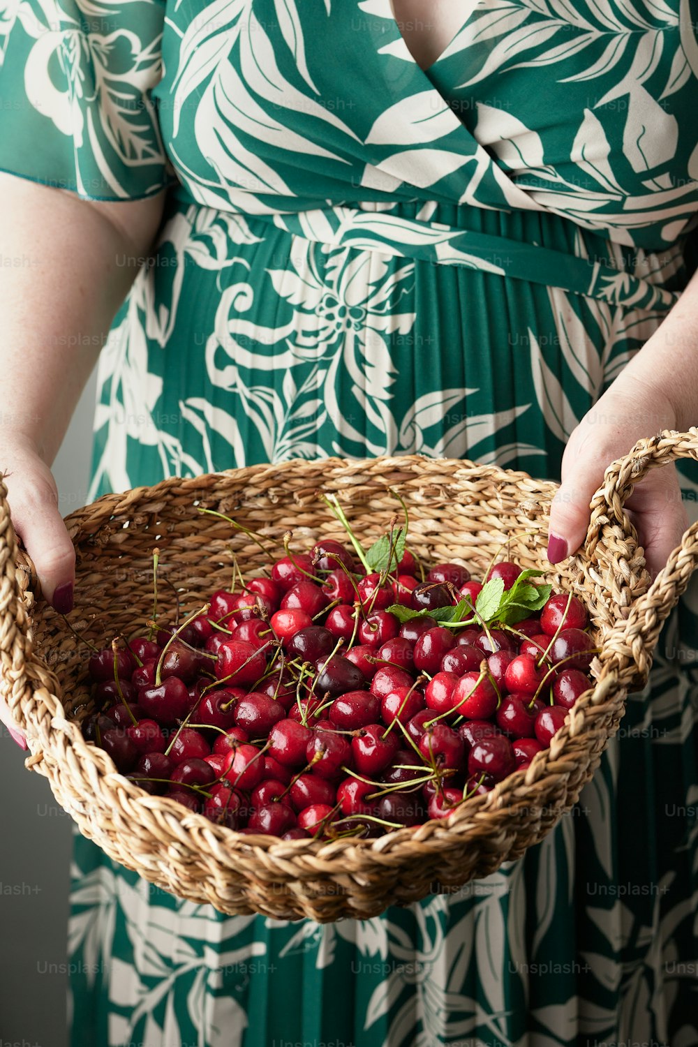 a woman in a dress holding a basket of cherries