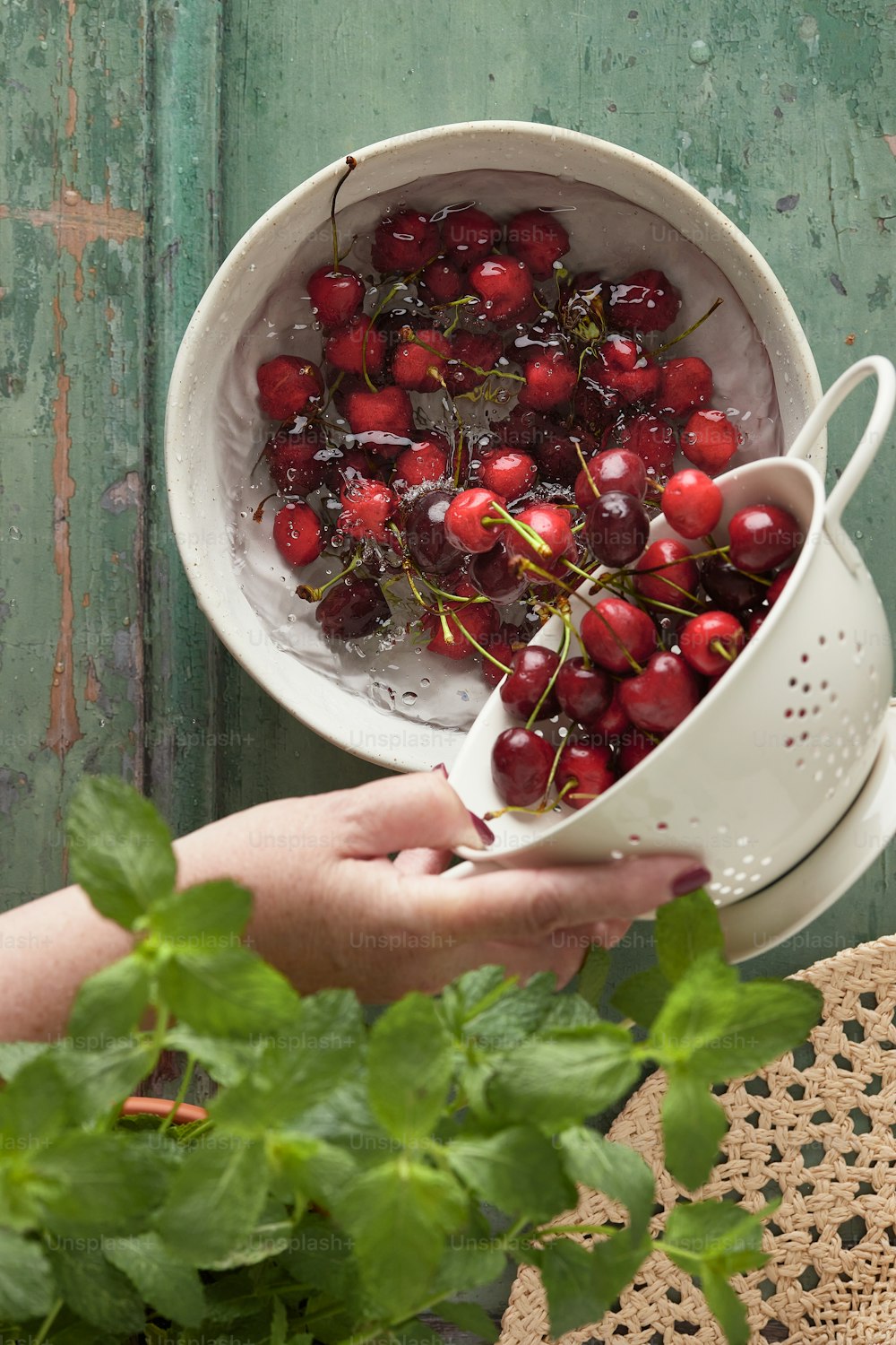 a person holding a colander full of cherries