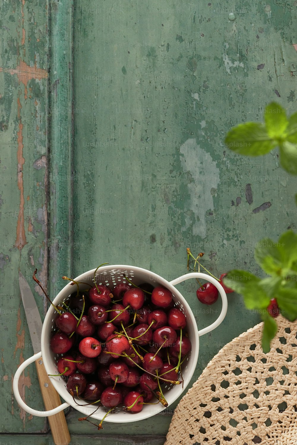a bowl of cherries on a table next to a potted plant
