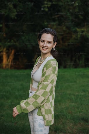 a woman standing in a field wearing a green and white cardigan