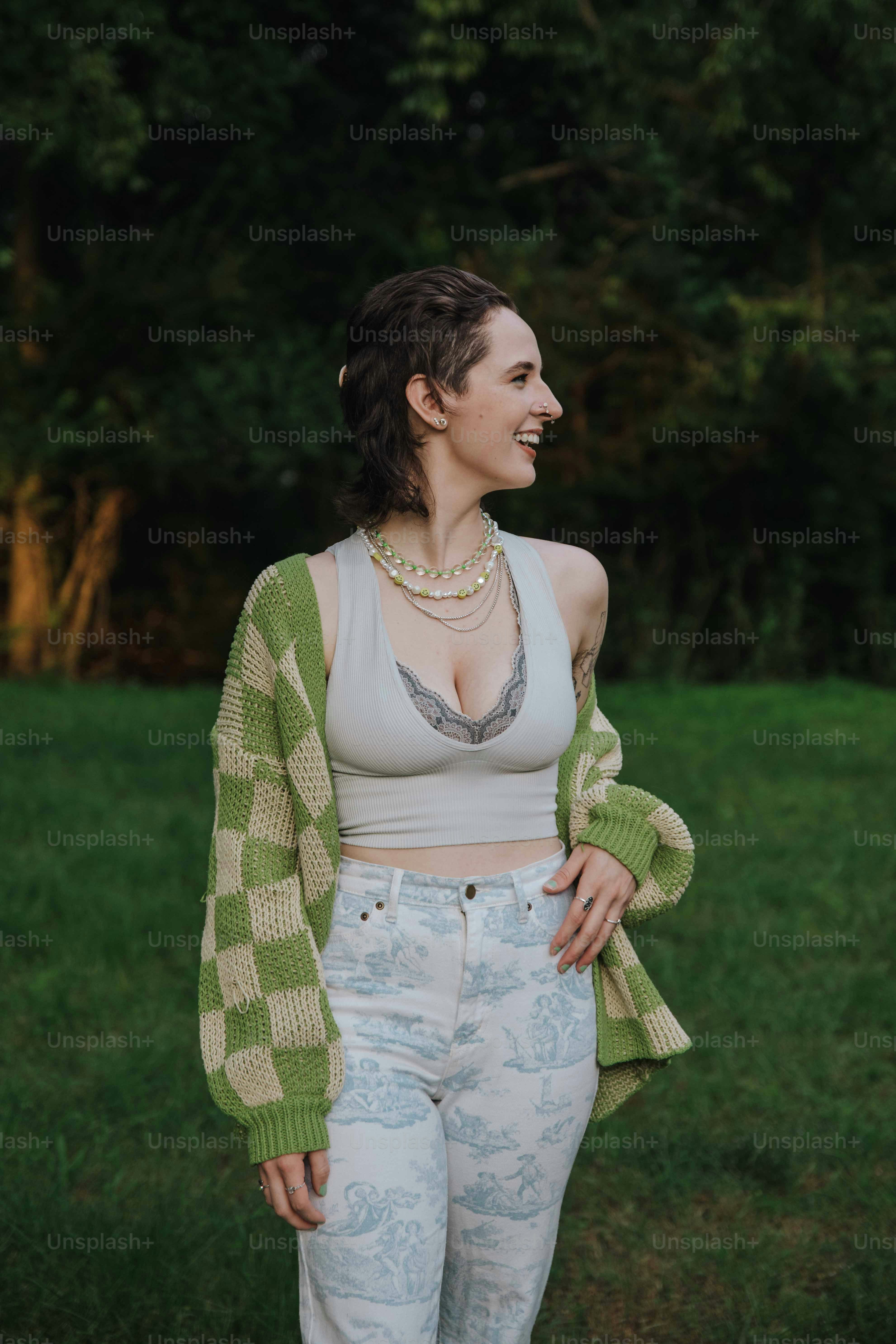 a woman standing in a field wearing a green and white cardigan