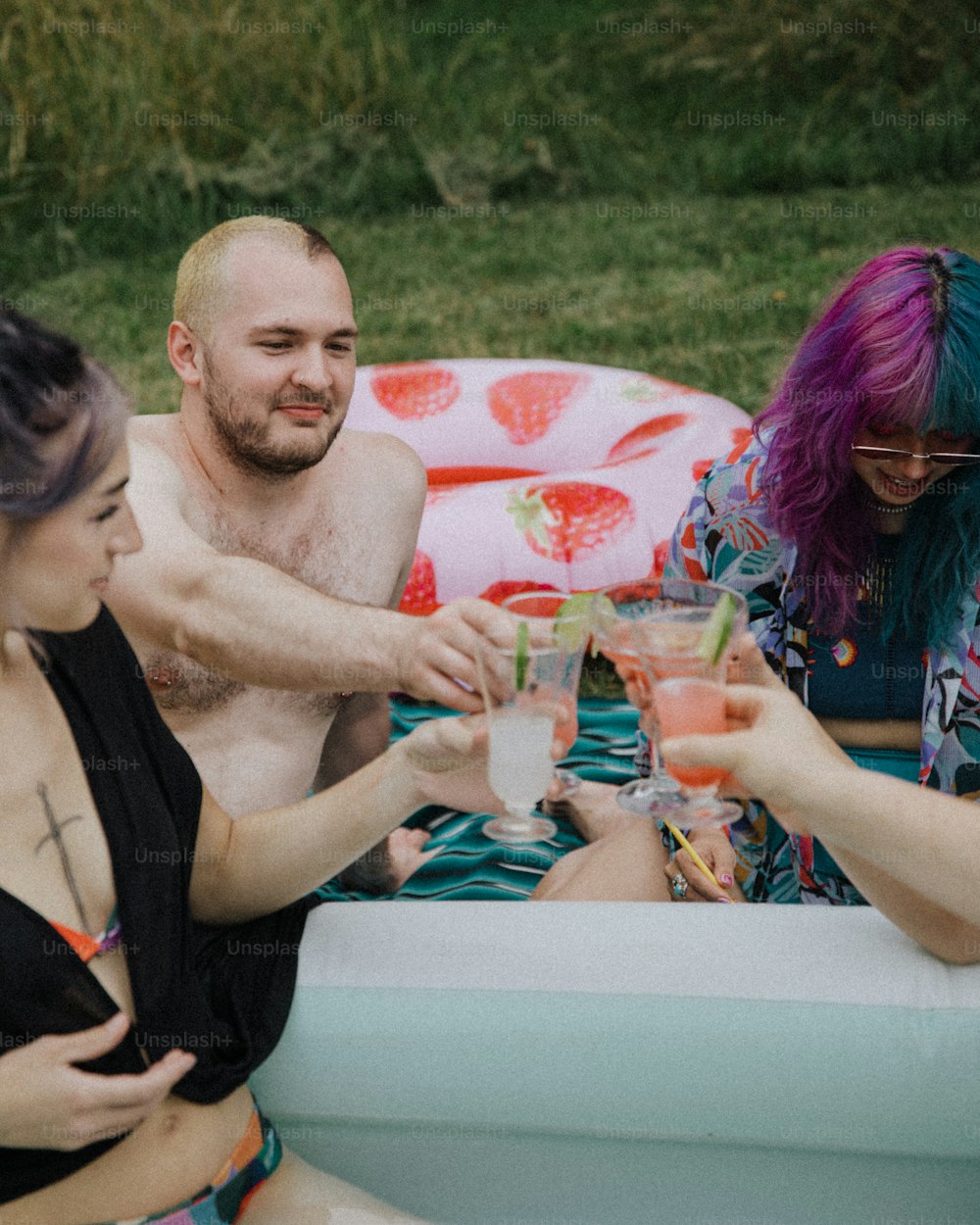 Un gruppo di persone sedute intorno a una piscina con bevande