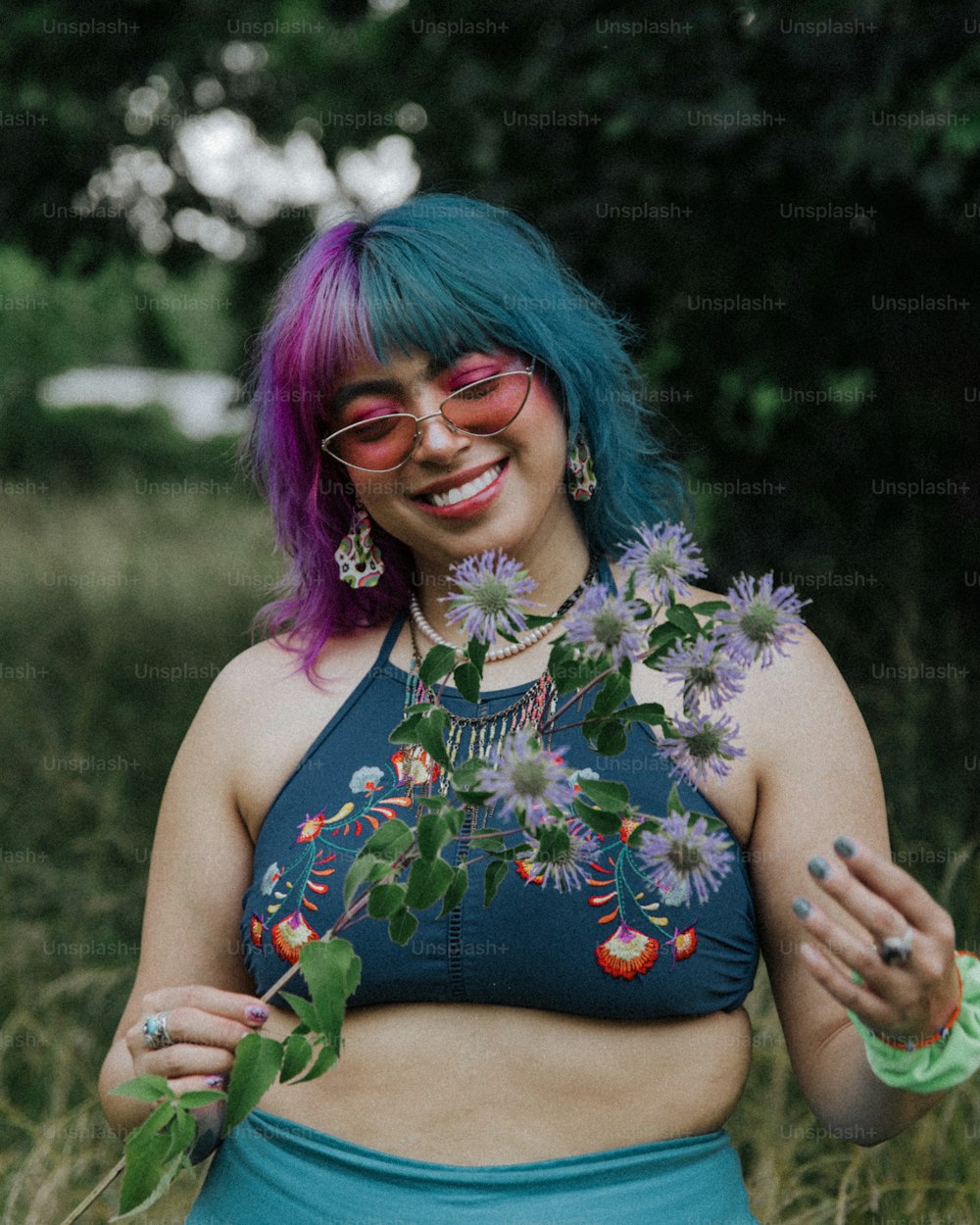 a woman with purple hair wearing a blue crop top