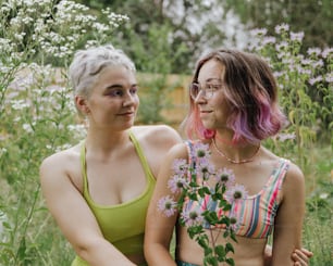 two women sitting next to each other in a field