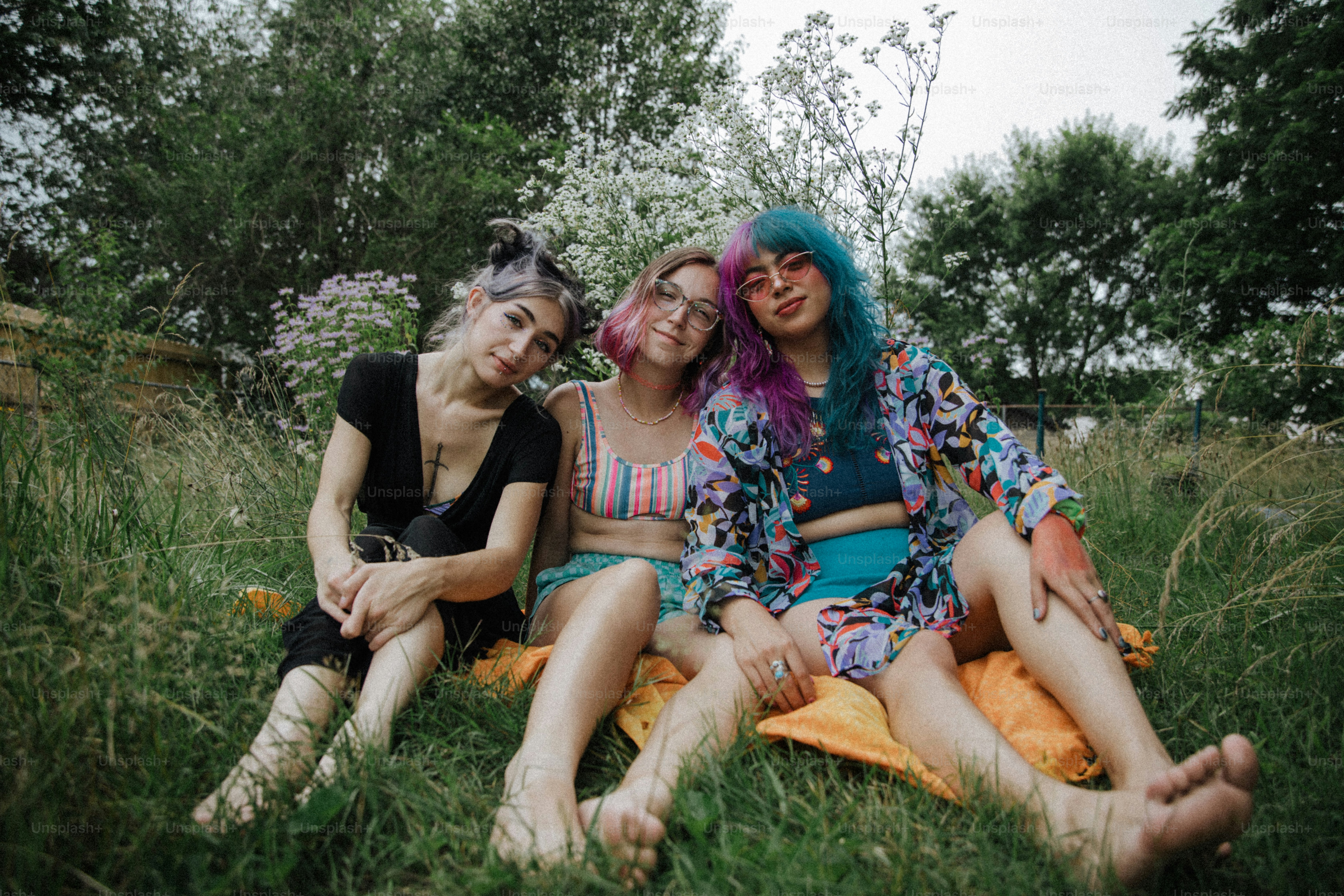 a group of women sitting on top of a lush green field
