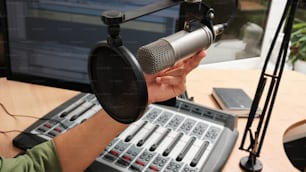 uma pessoa segurando um microfone na frente de uma mesa de som