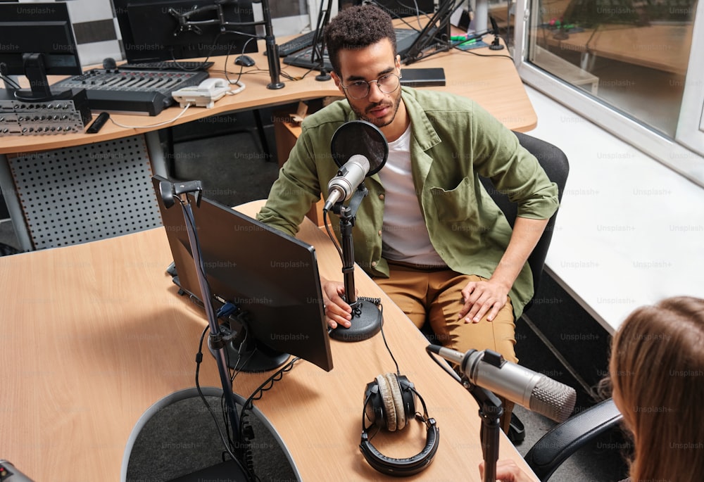 a man sitting in front of a microphone next to a woman