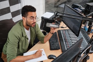 a man sitting at a desk in front of a microphone