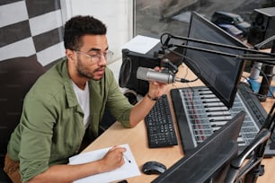 ein mann, der an einem schreibtisch vor einem mikrofon sitzt