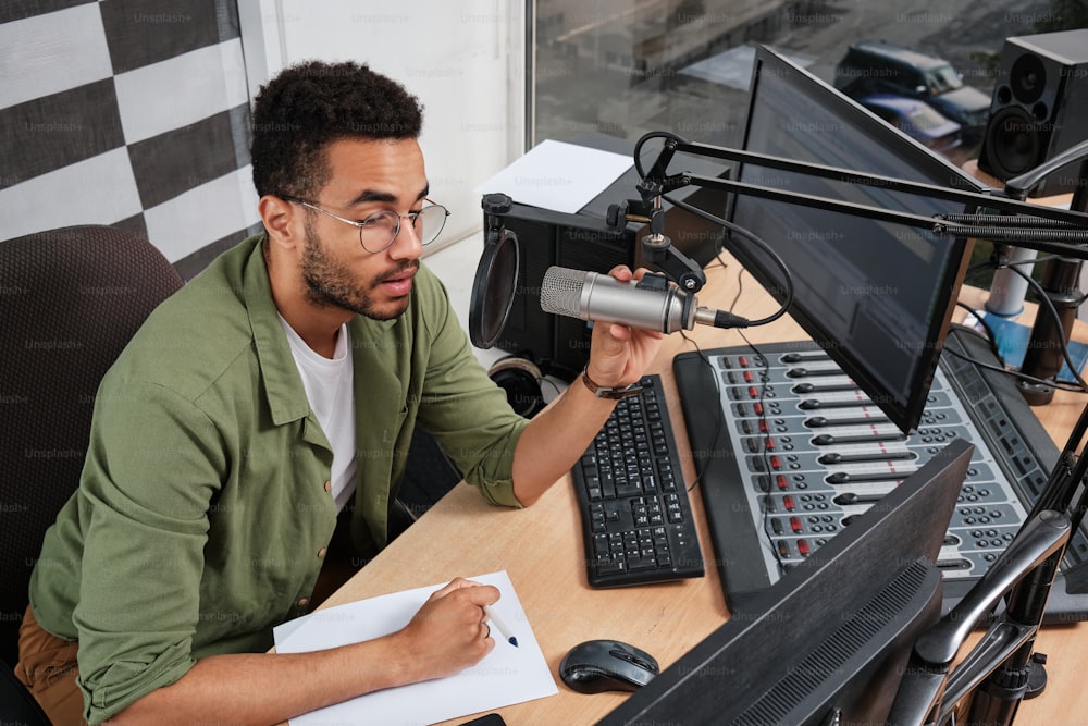 a man sitting at a desk in front of a microphone