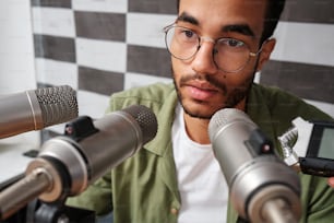 Un uomo con gli occhiali che tiene un cellulare davanti ai microfoni