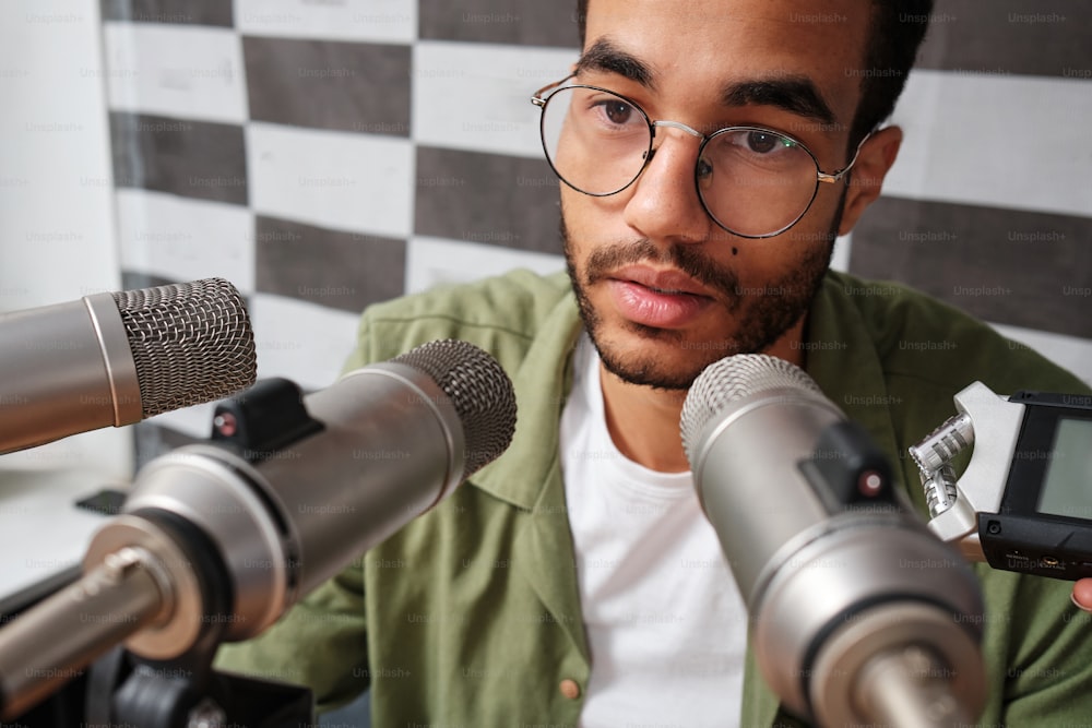 a man with glasses holding a cell phone in front of microphones