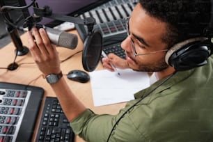 a man wearing headphones sitting in front of a microphone