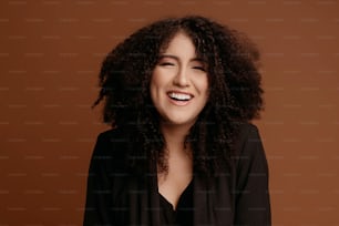 a woman with curly hair smiling at the camera
