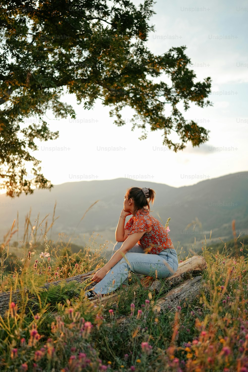 a woman sitting on a rock talking on a cell phone