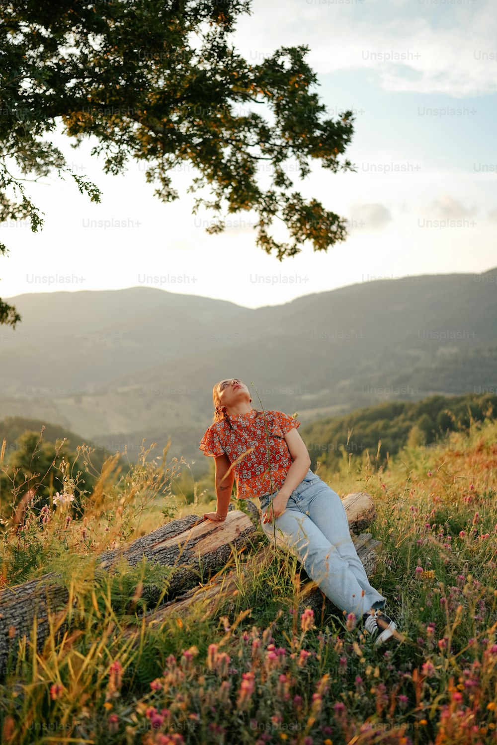 a woman sitting on a log in a field