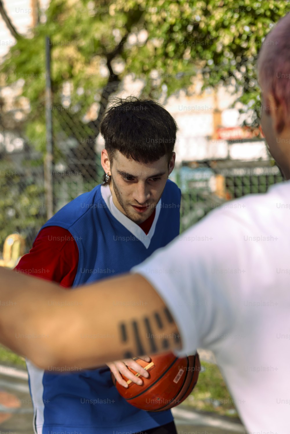 um homem com uma tatuagem no braço segurando uma bola de basquete