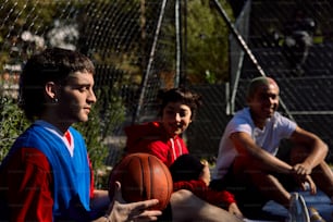 a group of men sitting on the ground with a basketball