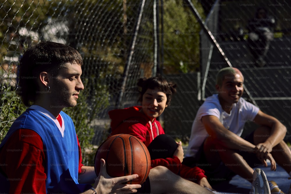 a group of men sitting on the ground with a basketball